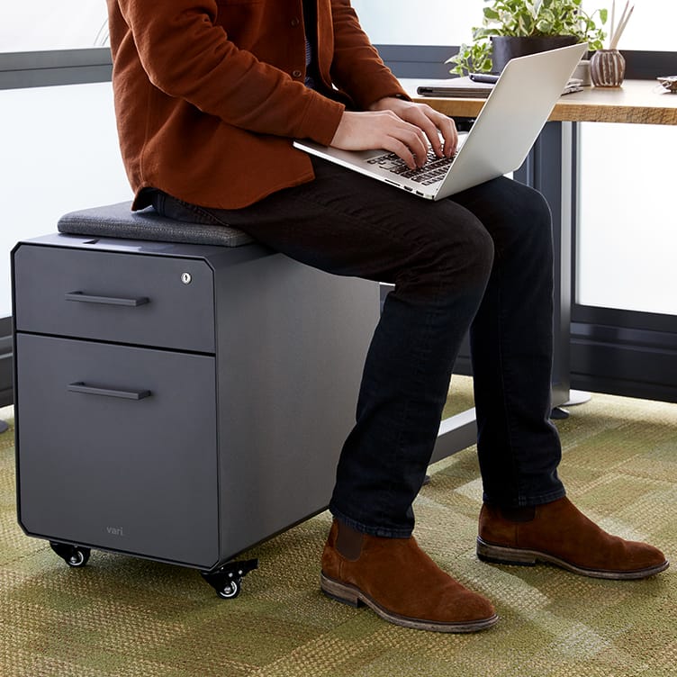 professional seated on storage seat while working on laptop