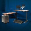 vari electric standing desk, table, and accessories in home office with blue background to highlight vari products